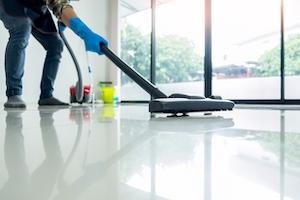 Young attractive man is cleaning vacuum commercial cleaning equipment on floor at home helping wife.